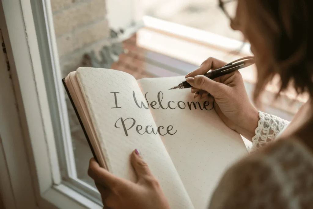 Hands writing a positive affirmation in a journal as part of a new moon ritual to manifest intentions and welcome new beginnings.